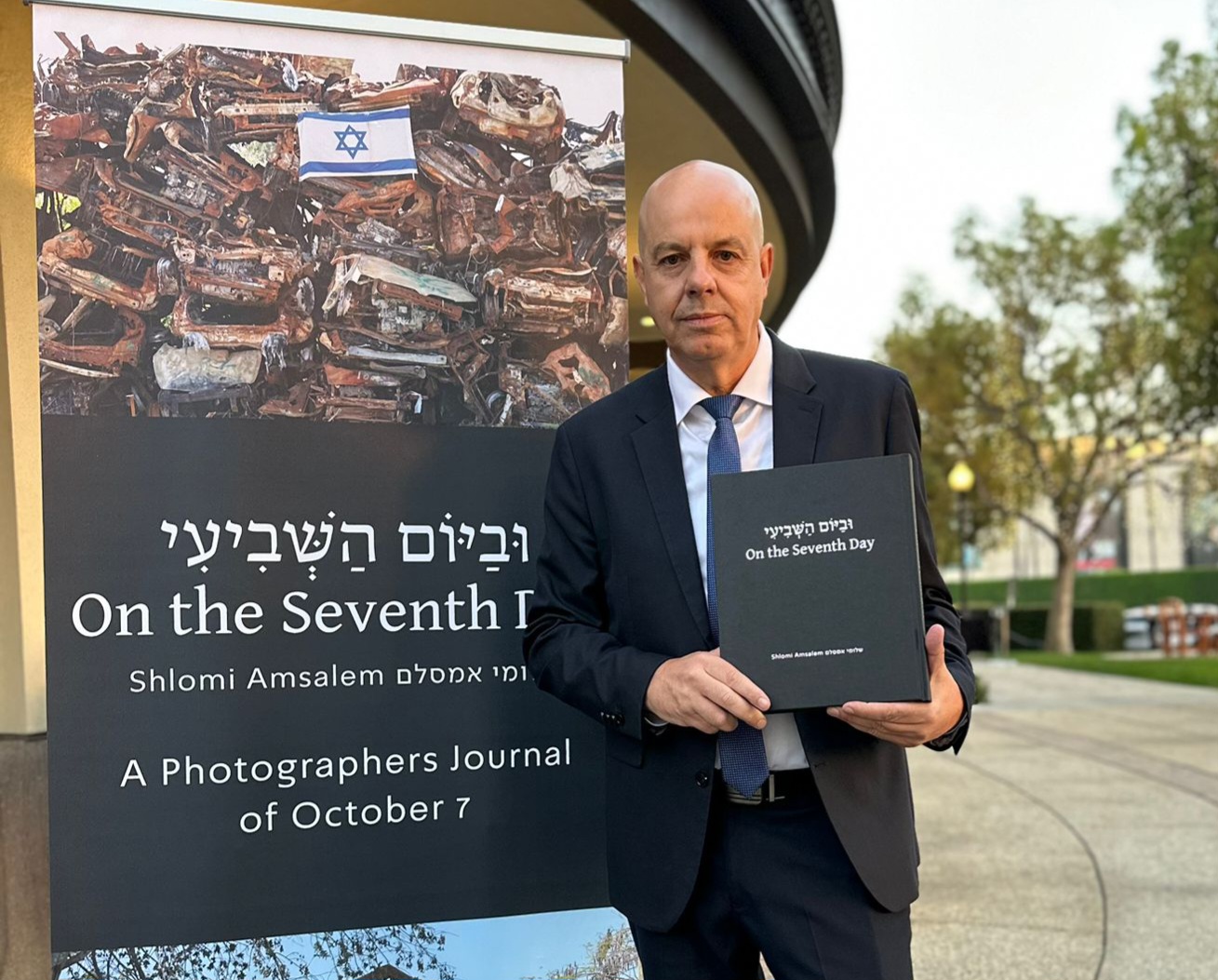 ספר ״וביום השביעי״ לצד כרזת הספר באירוע החשיפה בלוס אנג׳לס