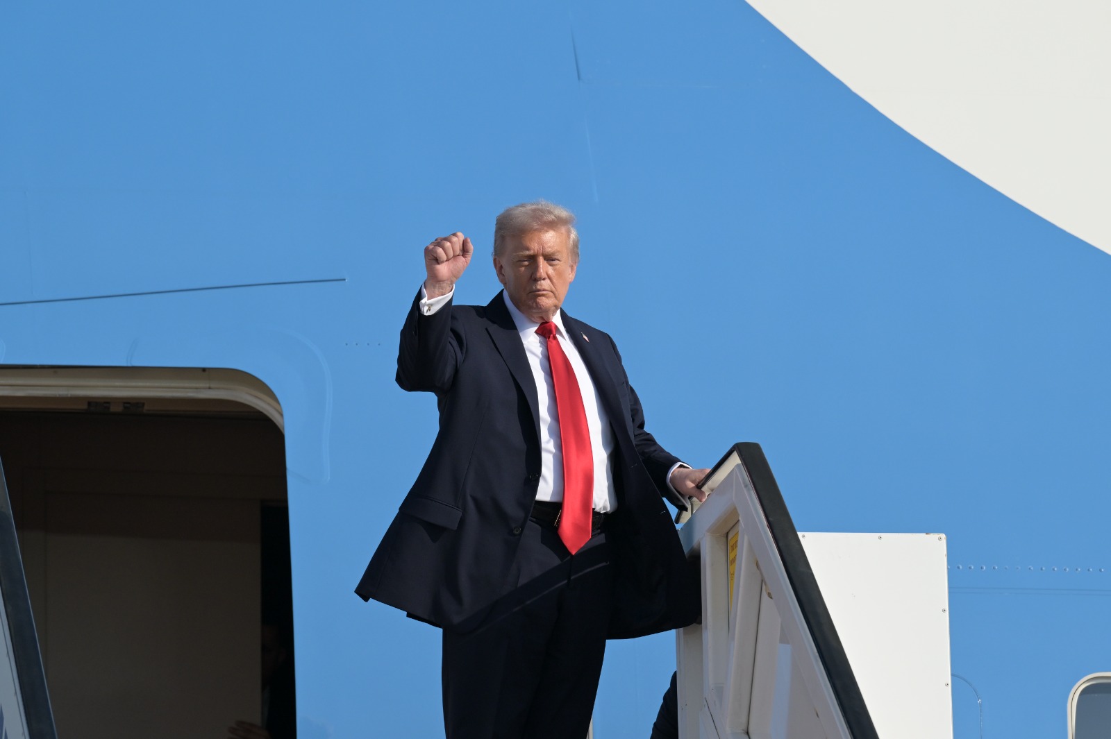 Trump raises a fist, the fuselage of Air Force One filling the frame